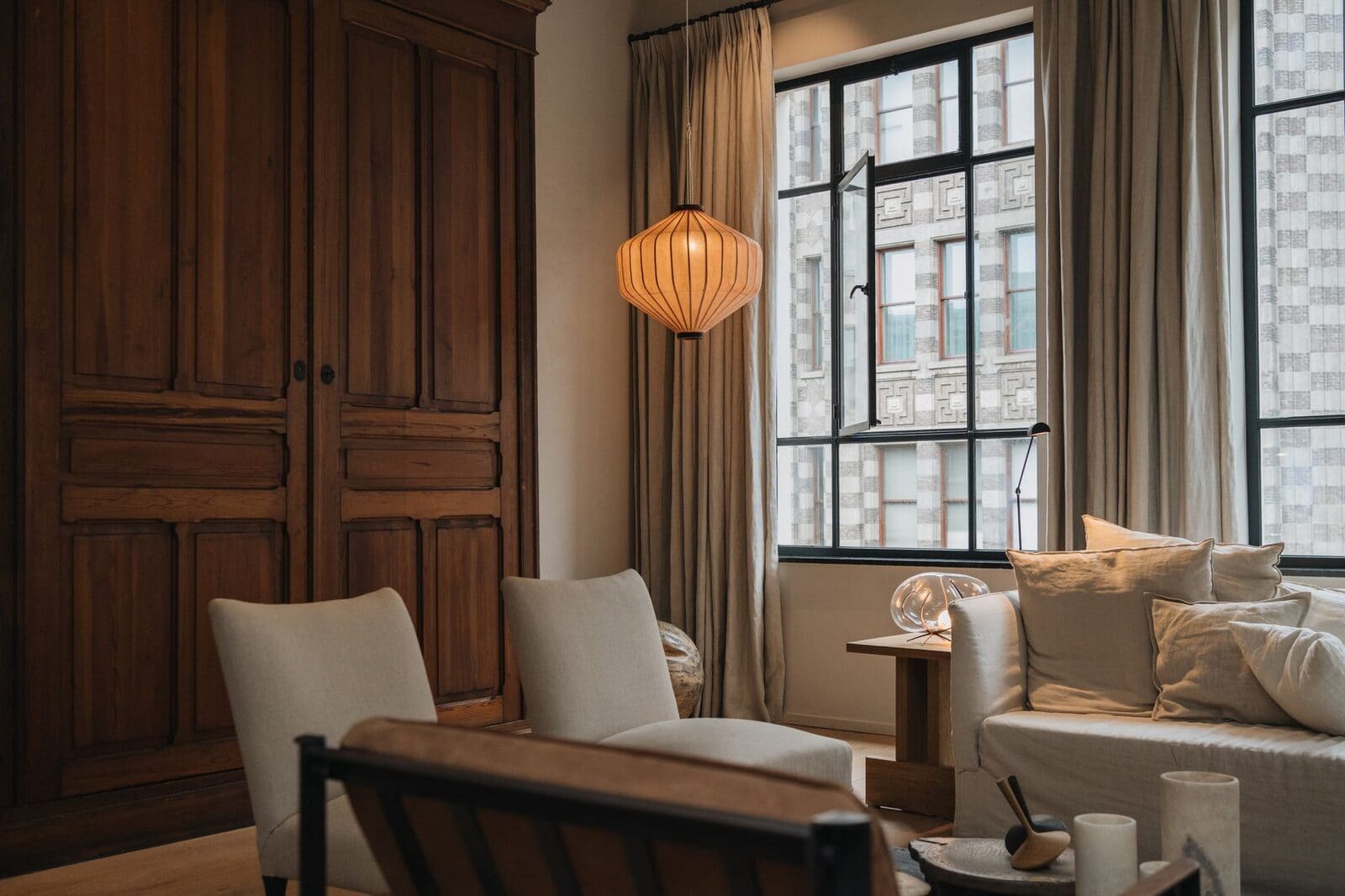 Stylish Amsterdam living room interior featuring wooden furniture and large windows.