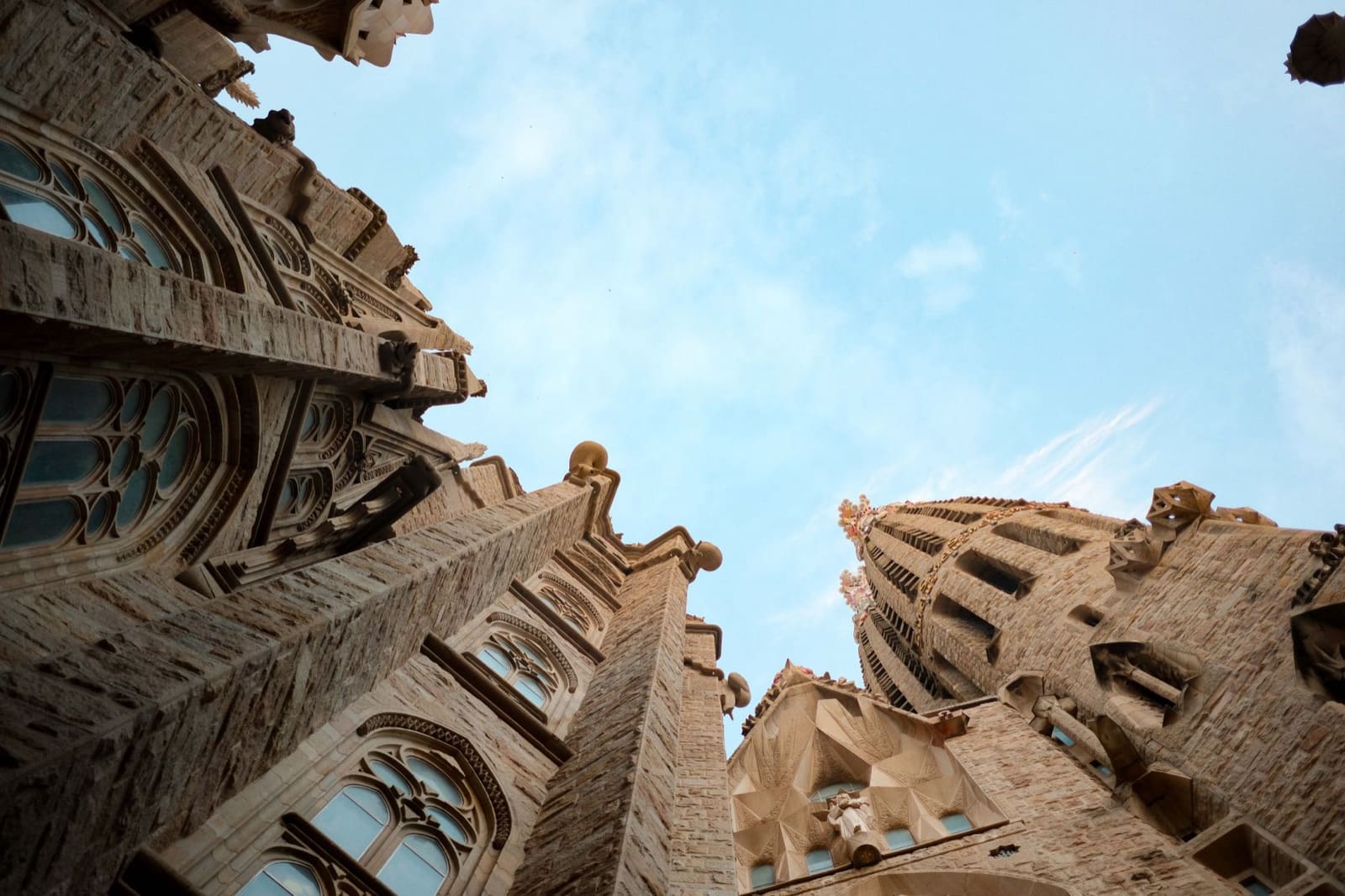 Upward view of Sagrada Familia towers in Barcelona with clear blue sky.