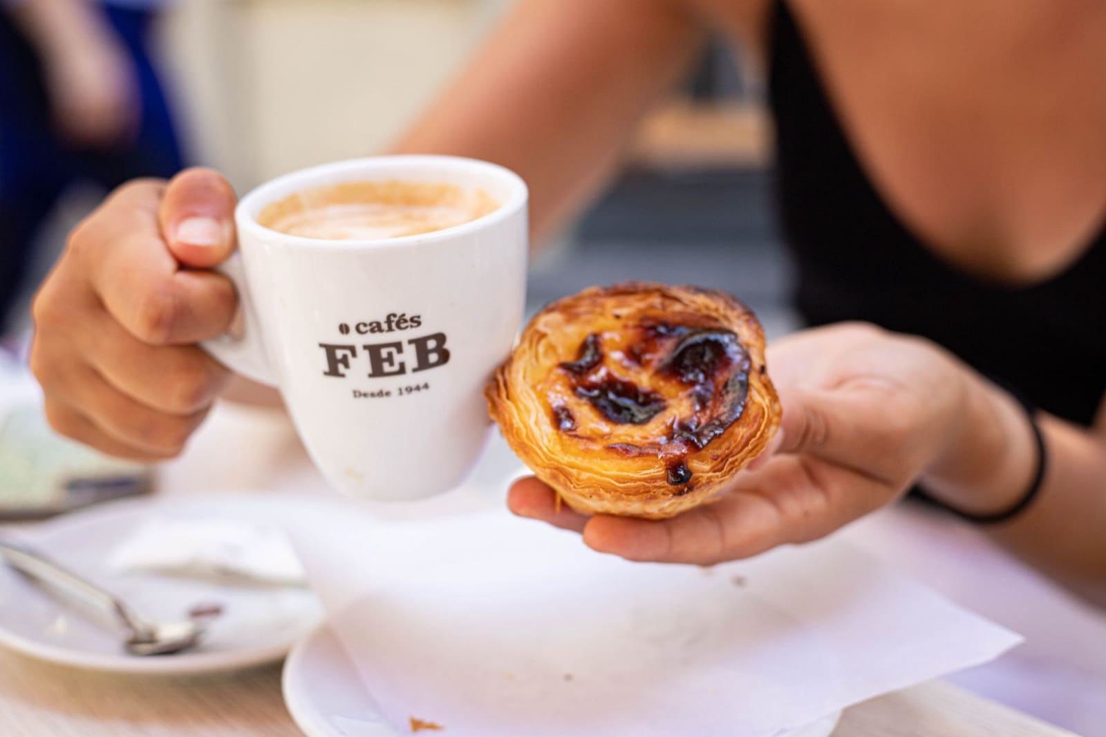A close-up of a delicious pastel de nata with a hot cup of coffee, perfect for a sweet snack.